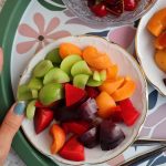 Top view of a colorful fruit platter with cherries, apricots, and plums on a decorative tray.
