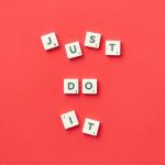 Motivational phrase 'Just Do It' spelled with Scrabble letters on a red background.